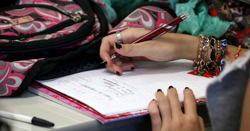 Mão de uma aluna em cima de um caderno escolar. Foto: Cecília Bastos