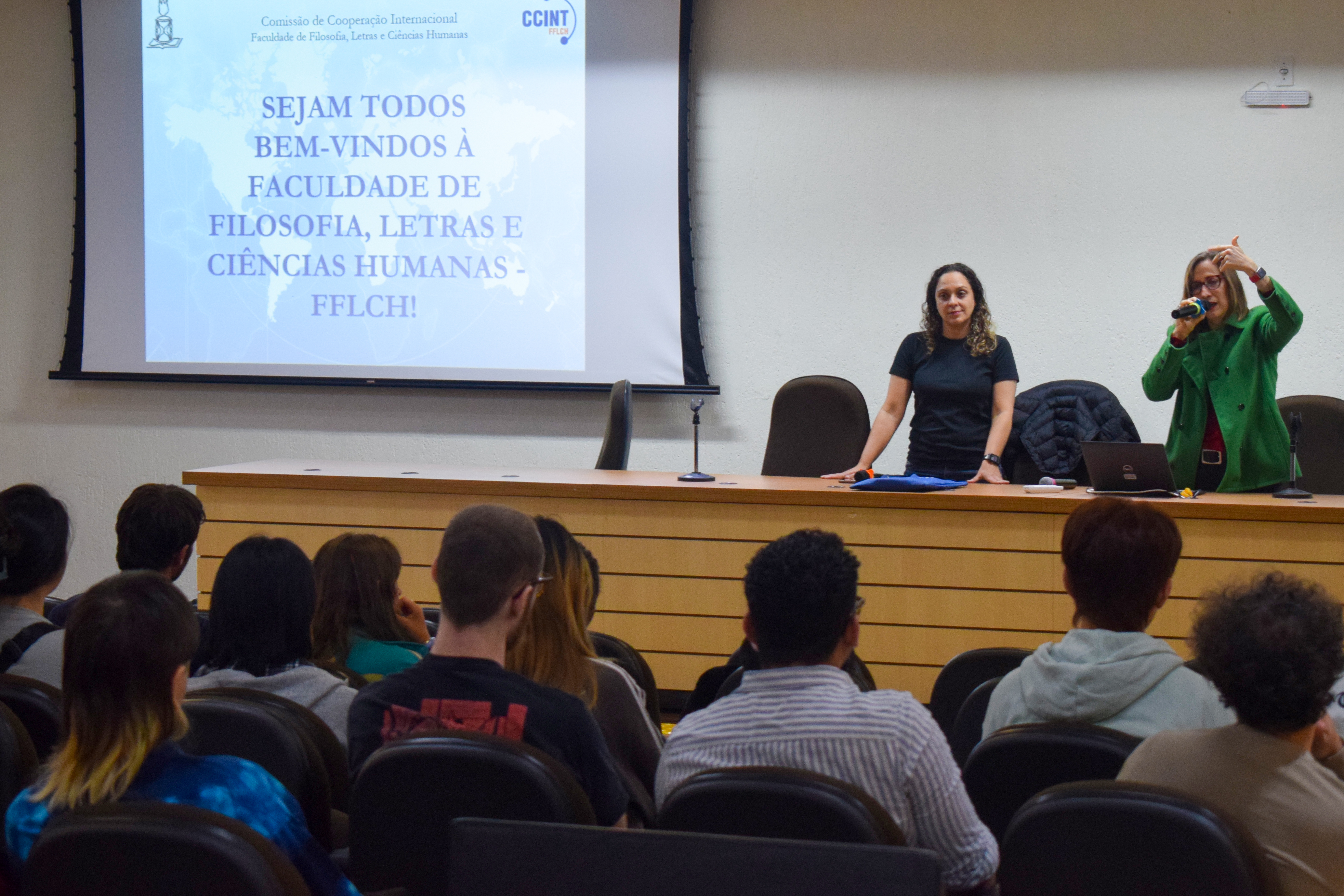 Duas mulheres em pé apresentando no auditório
